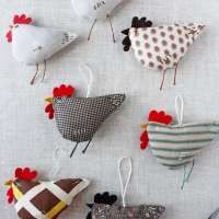 several different types of birds hanging from strings on a white table cloth background with scissors