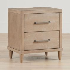 a wooden nightstand sitting on top of a hard wood floor next to a white wall