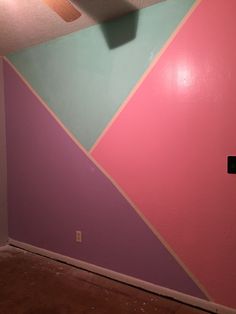 an empty room with pink, blue and green walls in the corner that is being painted