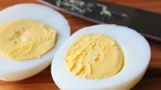 two hard boiled eggs sitting next to a knife