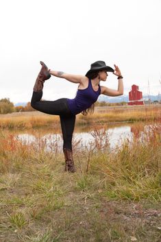 a woman wearing a cowboy hat and black leggings is doing a yoga pose