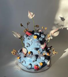 a blue cake with flowers and birds on it's top is casting a shadow