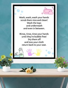 a table with some flowers on it and a poster above it that says wash, wash your hands scrub them nice and clean