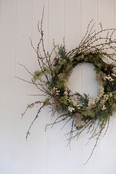 a wreath hanging on the wall with white flowers and greenery