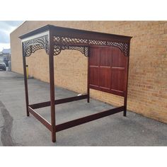 a wooden bed frame sitting in front of a brick building