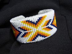 a beaded bracelet with an orange, yellow and blue star design on the side