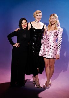 three women standing next to each other in front of a blue background