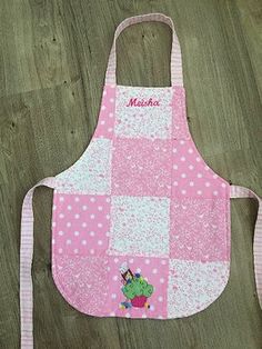 a child's apron with pink and white polka dots on it, sitting on a wooden floor