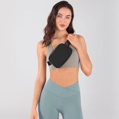 a woman in grey sports bra and leggings holds up her waist bag to the side