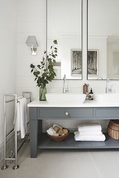 a bathroom vanity with two mirrors above it and towels on the bottom shelf next to it