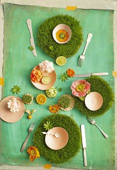 the table is set with plates and bowls filled with flowers, lemons, and oranges