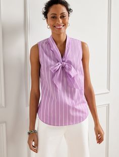 A playful tie at the neck adds an irresistibly feminine touch to this blousy shell. Crafted with fresh stripe print. This beautifully detailed top looks great alone or under a blazer! Features Sleeveless Hits Above Hip Tie Neck Pullover Curved hem Imported Fit: Misses: 26 1/2"; Petite: 25"; Plus: 29 1/4" Material: 100% Cotton Care: Machine Wash Cold; Only Non-Chlorine Bleach When Needed; Tumble Dry Low; Warm Iron, If Needed | Tie Neck Shell Sweater - Morning Stripe - 100% Cotton Talbots Classic Purple Top With Buttons, Purple Top With Spread Collar And Button Closure, Collared Purple Blouse With Button Closure, Purple Collared Blouse With Button Closure, Talbots Spring 2024 Preview, Floral Ruffle Top, Ruffle Trim Top, Tie Neck Tops, Classic Style Women