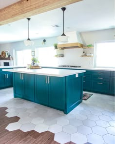 a large kitchen with blue cabinets and white tile flooring, along with wooden beams in the ceiling