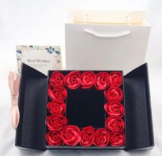 a box with red roses in it next to a pair of scissors and a card