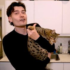 a man holding a cat in the kitchen