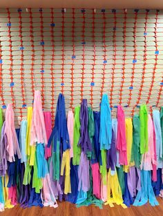 colorful streamers are hanging on the wall in front of a wooden floor and orange string