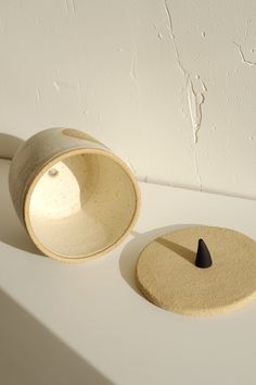 two white bowls sitting on top of a table next to each other, one with a black tip