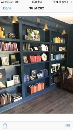 the room is full of books and pictures on the bookcases, along with a leather chair