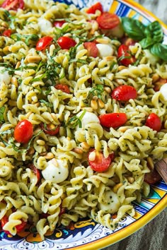 a plate full of pasta salad with tomatoes and spinach