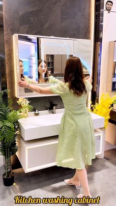 a woman in a green dress is looking at her reflection in the mirror while she brushes her teeth