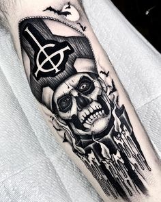 a man's arm with a black and white tattoo on it, featuring a skull holding a hammer