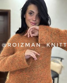 a woman in an orange sweater posing for a photo with her hands on her hips