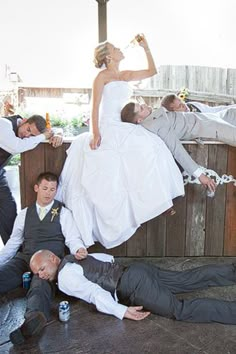 a bride and groom laying on the ground in front of other people with their arms around each other