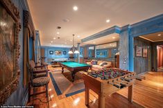 a large living room with pool table and foosball in the center is lit by recessed lighting