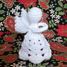 a crocheted angel ornament sitting on top of a floral table cloth