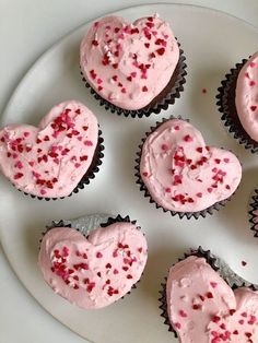 cupcakes with pink frosting and sprinkles arranged on a plate