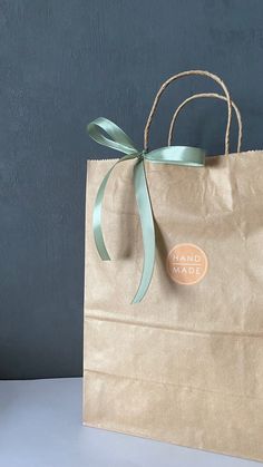 a brown paper bag with a green ribbon tied around it and a label on the front