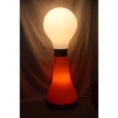 an orange light bulb sitting on top of a table next to a white lamp shade