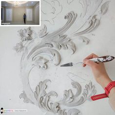 a person is using a paintbrush to decorate a wall with flowers and leaves on it