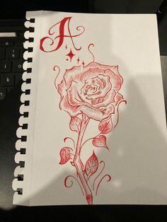 a drawing of a rose with the letter a in it's center on top of a notebook