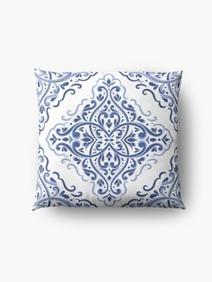 a blue and white pillow with an ornate design on the front, sitting against a white background