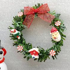 a christmas wreath and snowman ornament sitting next to each other