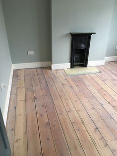 an empty room with wood floors and a fireplace