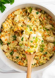 chicken and rice in a white bowl with a wooden spoon on the side, ready to be eaten