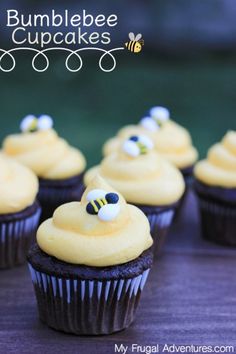 cupcakes with yellow frosting and bees on them are sitting on a table