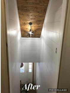 an empty hallway with a ceiling fan and wood paneling on the wall above it