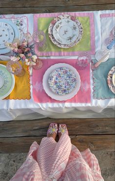 an overhead view of a table set with plates and napkins, pink slippers on the ground