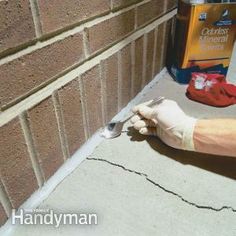 a person wearing gloves and holding a fork near a brick wall with cleaning products on it