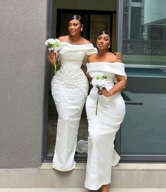 two women in white dresses standing next to each other