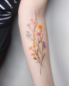 a woman's arm with flowers on it and a tattoo that says wildflowers