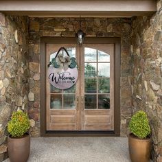 two potted plants sit outside the front door of a home that is decorated with welcome signs