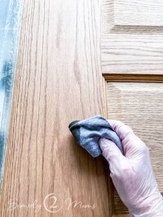 a person in white gloves cleaning a wooden door with a microfiber cloth on it