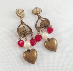 These Victorian Revival drop hearts earrings are stunning with a top faux Mabe pearl in a filigree circle, an open inverted etched heart with a dangle brass heart with a prong-set red stone, two dangle red glass hearts, a faux pearl bead and a bottom large puffy brass heart. They are spectacular!! measure 2 7/8 from the top of the wire to the bottom of the beads and measure 5/8 in width are pierced post earrings and light weight are in excellent condition and look awesome on! are so very beautif Retro Heart-shaped Earrings For Valentine's Day, Retro Heart Earrings For Valentine's Day, Vintage Metal Heart Earrings For Valentine's Day, Retro Jewelry For Valentine's Day Party, Vintage Metal Heart Earrings, Pierced, Vintage Dangle Heart Beads Jewelry, Vintage Heart-shaped Earrings For Party, Vintage Dangle Jewelry With Heart Beads, Vintage Jewelry With Heart Beads And Dangle Shape