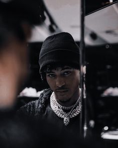 a young man wearing a black hat looking at himself in the mirror with his reflection