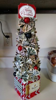 a christmas tree made out of dollar bills on top of a counter with a red and white tag