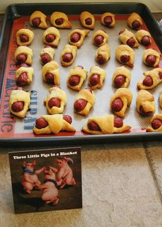 there are many pigs in a blanket on the baking sheet, and one is half eaten